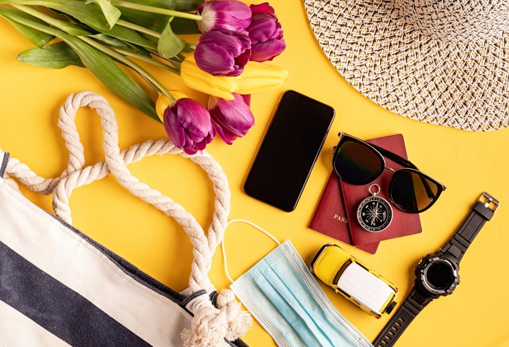 Flat lay travelling gear with passports, smartphone, sunglasses and compass on yellow background