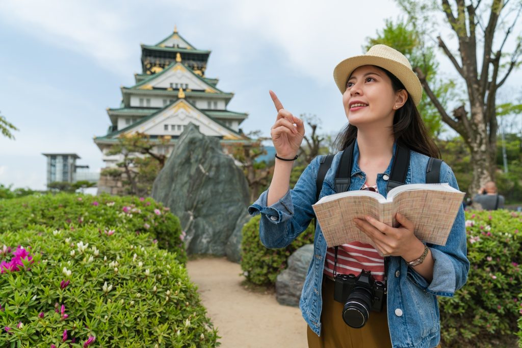 girl visiting Osaka castle using travel guide